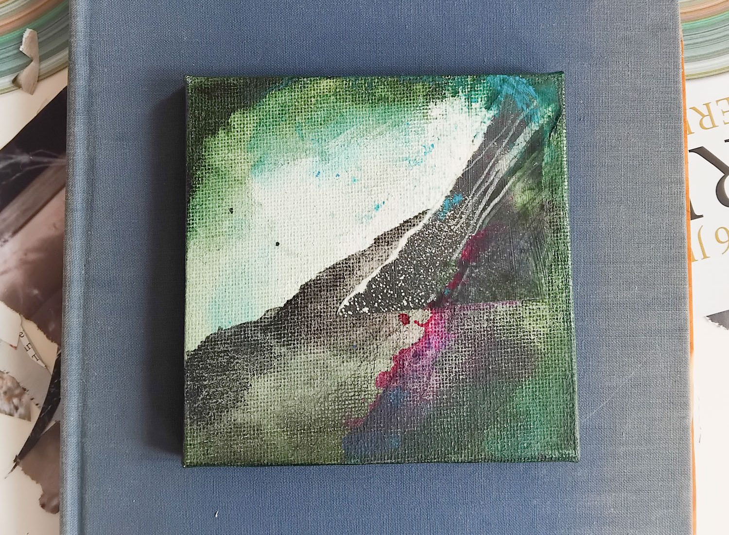 Abstract painting on canvas with dark mountain incline, greens and pink splashes