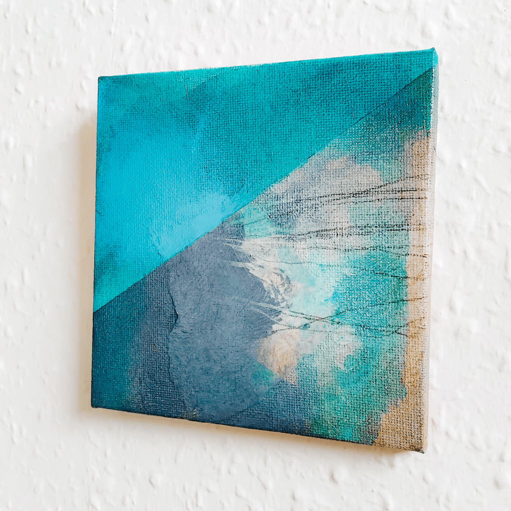 Painting on canvas hung on a white wall, with drawn carbon pencil lines, abstract cliffs in collage and ink, and turqoise blue paint